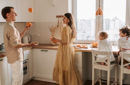 Joyful family scene with parents and children playing in a bright kitchen.